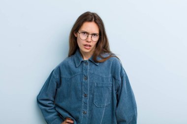 young adult pretty woman feeling puzzled and confused, with a dumb, stunned expression looking at something unexpected