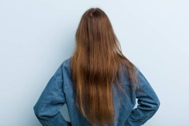 Genç ve güzel bir kadın, kafası karışık ya da dolgun ya da şüphe ve soru dolu, merak ediyor, elleri kalçasında, dikiz aynasından.