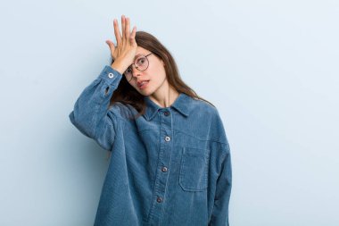 young adult pretty woman raising palm to forehead thinking oops, after making a stupid mistake or remembering, feeling dumb