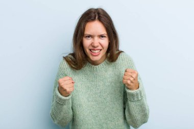 Genç ve güzel bir kadın sinirli, sinirli, sinirli bakışlar ve sıkı yumruklar ile agresif bir şekilde bağırıyor.