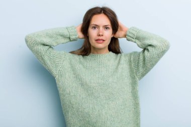 Genç ve güzel bir kadın stresli, endişeli ya da korkmuş hissediyor. Elleri başının üstünde, hatayla panikliyor.