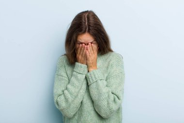 young adult pretty woman feeling sad, frustrated, nervous and depressed, covering face with both hands, crying