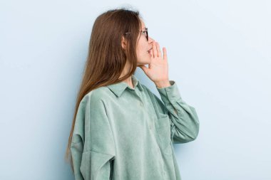 young adult pretty woman profile view, looking happy and excited, shouting and calling to copy space on the side