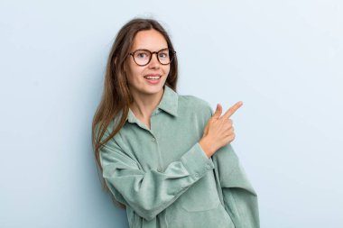 Genç ve güzel bir kadın heyecanlı ve şaşırmış görünüyor. Yana ve yukarıya bakıp boşluğu kopyalıyor.