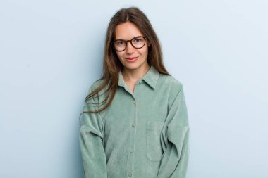 Genç ve güzel bir kadın pozitif ve kendinden emin gülümsüyor. Tatmin olmuş, arkadaş canlısı ve mutlu görünüyor.