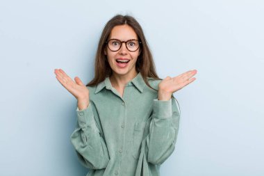 Genç ve güzel bir kadın mutlu ve heyecanlı görünüyor. Beklenmedik bir sürprizle şoke olmuş. İki eli de açık.