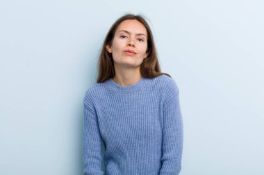 Genç ve güzel bir kadın tatlı, eğlenceli, mutlu, sevimli bir yüz ifadesiyle dudaklarını birbirine bastırıyor.