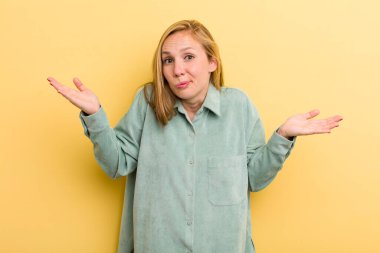 young adult blonde pretty woman looking puzzled, confused and stressed, wondering between different options, feeling uncertain