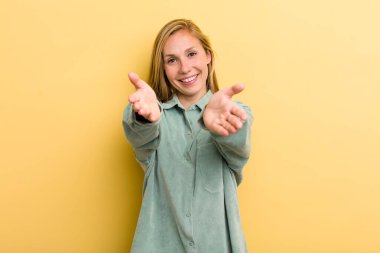 Genç, sarışın, güzel bir kadın neşeyle gülümsüyor sıcak, dostça, sevgi dolu bir kucaklama yapıyor, mutlu ve sevimli hissediyor.