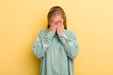 Genç, sarışın, güzel bir kadın üzgün, hayal kırıklığına uğramış, gergin ve depresif, iki eliyle yüzünü kaplayan, ağlayan.