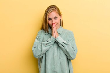 Genç, sarışın, güzel bir kadın endişeli, umutlu ve dindar hissediyor, sadık bir şekilde avuç içiyle dua ediyor, af diliyor.