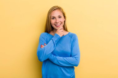 Genç sarışın güzel kadın gülümsüyor, hayattan zevk alıyor, mutlu, arkadaş canlısı, tatmin olmuş ve tasasız.