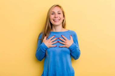 Genç, sarışın, güzel, mutlu görünen, şaşırmış, gururlu ve heyecanlı, kendini gösteren bir kadın.