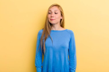 Genç, sarışın, güzel bir kadın mutlu düşünceler ve fikirler düşünüyor, hayal kuruyor, kenarda yer arıyor.