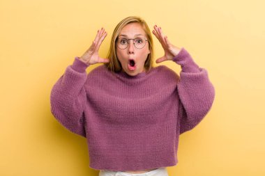 Genç, sarışın, güzel bir kadın elleri havada bağırıyor. Öfkeli, sinirli ve üzgün.