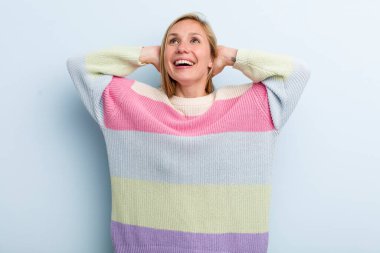 Genç, sarışın güzel bir kadın gülümsüyor ve rahatlıyor, tatmin oluyor ve kaygısızca gülüyor.