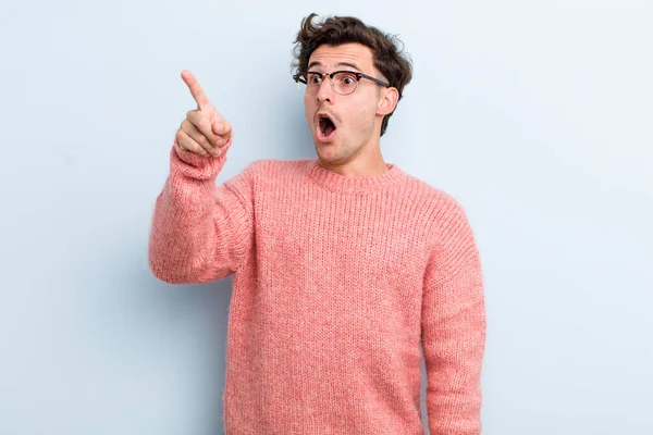 Genç yakışıklı adam şaşkın ve şaşırmış hissediyor, hayranlıkla yukarı bakıyor, şaşırmış, ağzı açık bakıyor.