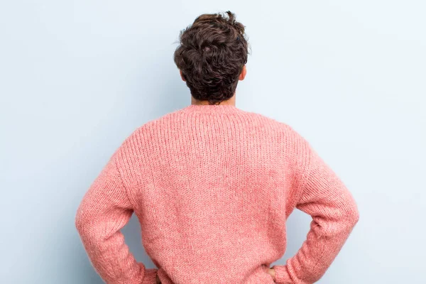 Genç, yakışıklı bir adam kafası karışık ya da dolu ya da şüphe ve soru dolu, merak ediyor, elleri kalçasında, dikiz aynasından.