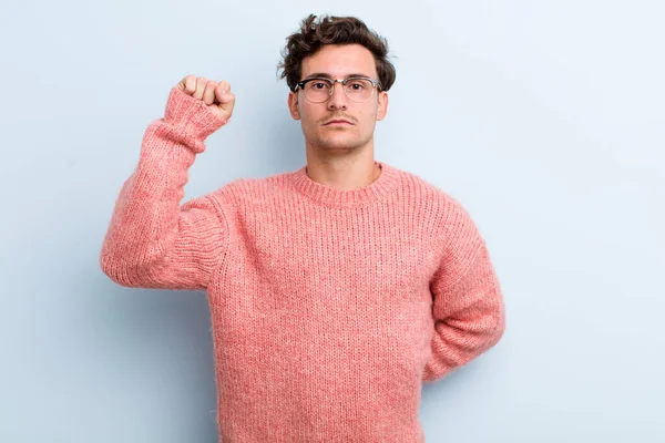 Genç yakışıklı adam ciddi, güçlü ve asi hissediyor, yumruğunu kaldırıyor, protesto ediyor ya da devrim için savaşıyor.