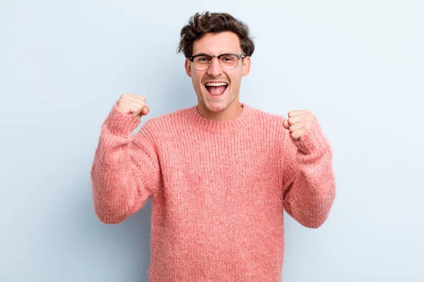 Genç yakışıklı adam mutlu, pozitif ve başarılı hissediyor, zaferi, başarıları ya da iyi şansı kutluyor.