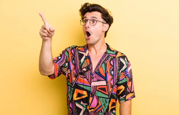 Genç yakışıklı adam şaşkın ve şaşırmış hissediyor, hayranlıkla yukarı bakıyor, şaşırmış, ağzı açık bakıyor.