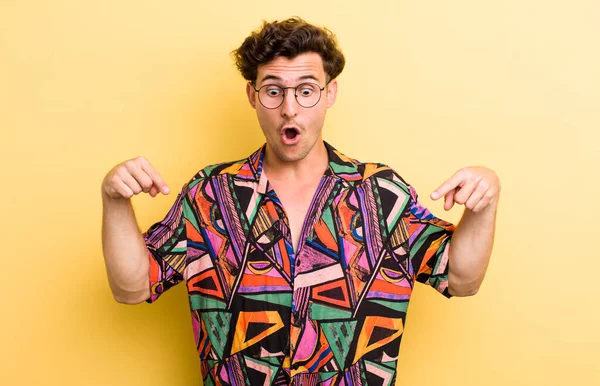 Genç yakışıklı adam şok olmuş, ağzı açık ve şaşkın, inançsızlık ve şaşkınlık içinde bakıyor ve onu işaret ediyor.