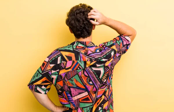 Genç yakışıklı bir adam bilgisiz ve kafası karışık hissediyor, bir çözüm düşünüyor, eli kalçasında, diğeri kafasında, dikiz aynasından.