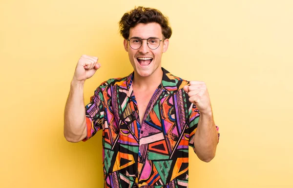 Genç yakışıklı adam mutlu, pozitif ve başarılı hissediyor, zaferi, başarıları ya da iyi şansı kutluyor.