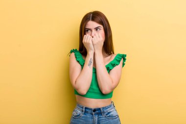 Genç ve güzel bir kadın endişeli, gergin, stresli ve korkmuş görünüyor. Tırnaklarını yiyor ve yanal fotokopi alanı arıyor.