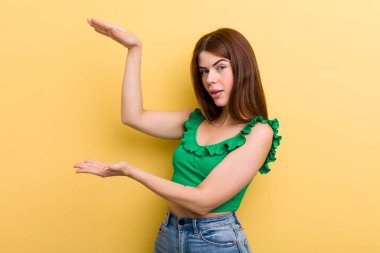 Genç ve güzel bir kadın gülümsüyor, mutlu, pozitif ve tatmin olmuş hissediyor, fotokopi alanında nesne ya da konsept tutuyor ya da gösteriyor