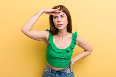 Genç ve güzel bir kadın şaşkınlık ve şaşkınlık içinde bakıyor. Alnı açık, uzaklara bakıyor, izliyor ya da arıyor.