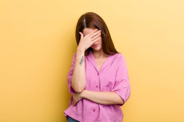 young adult pretty woman looking stressed, ashamed or upset, with a headache, covering face with hand