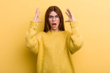 young adult pretty woman screaming with hands up in the air, feeling furious, frustrated, stressed and upset