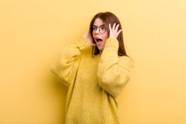 young adult pretty woman feeling happy, excited and surprised, looking to the side with both hands on face