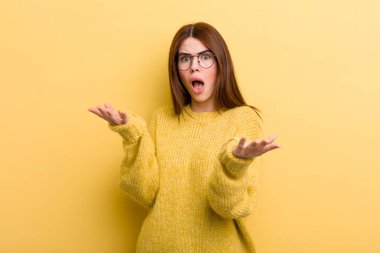 young adult pretty woman feeling extremely shocked and surprised, anxious and panicking, with a stressed and horrified look