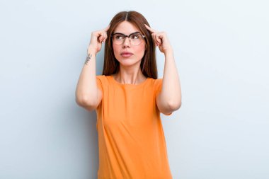 young adult pretty woman feeling confused or doubting, concentrating on an idea, thinking hard, looking to copy space on side
