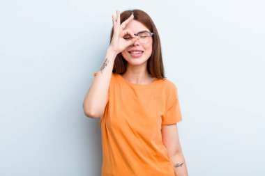 Genç ve güzel bir kadın mutlu bir şekilde gülümsüyor, şaka yapıyor ve gözetleme deliğinden bakıyor, sırları gözetliyor.