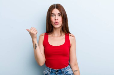 Genç ve güzel bir kadın inançsızlıktan şaşkın şaşkın bakıyor, yan taraftaki objeyi işaret ediyor ve 