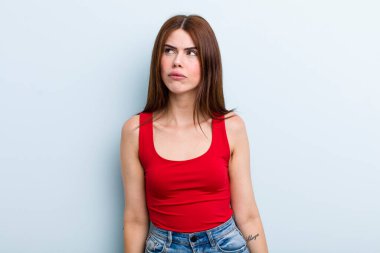 Genç ve güzel bir kadın kafası karışmış görünüyor, merak ediyor ya da çözmeye çalışıyor ya da düşünüyor.