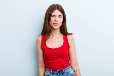 Genç ve güzel bir kadın mutlu ve arkadaş canlısı görünüyor, gülümsüyor ve sana olumlu bir tavırla göz kırpıyor.