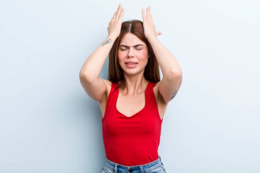 Genç ve güzel bir kadın stresli ve endişeli hissediyor, bunalımda ve hayal kırıklığına uğramış, iki elini de başa kaldırıyor.