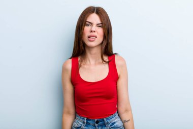 young adult pretty woman feeling puzzled and confused, with a dumb, stunned expression looking at something unexpected