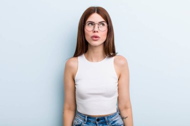 Genç, güzel bir kadın şok olmuş, mutlu, şaşkın ve şaşırmış hissediyor, ağzı açık bir şekilde yana bakıyor.