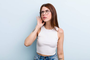 Genç ve güzel bir kadın ciddi ve meraklı görünüyor, dinliyor, gizli bir konuşma veya dedikodu duymaya çalışıyor, kulak misafiri oluyor.