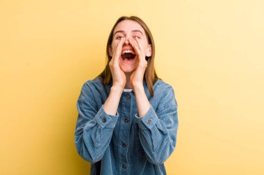 Genç ve güzel bir kadın mutlu, heyecanlı ve pozitif hissediyor. Elleri ağızda, bağırıyor.