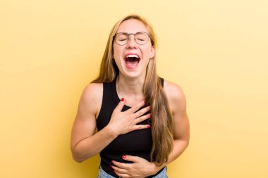 young adult  blonde woman laughing out loud at some hilarious joke, feeling happy and cheerful, having fun