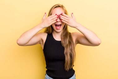 Genç sarışın kadın gülümsüyor ve mutlu hissediyor, iki eliyle gözlerini kapatıyor ve inanılmaz bir sürpriz bekliyor.