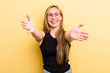 young adult  blonde woman smiling cheerfully giving a warm, friendly, loving welcome hug, feeling happy and adorable