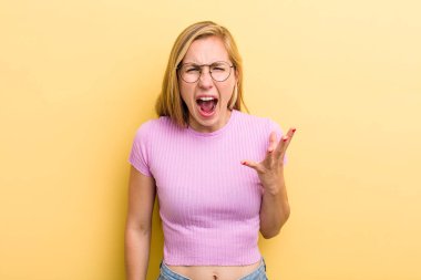 young adult  blonde woman looking angry, annoyed and frustrated screaming wtf or whats wrong with you 