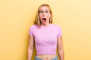 Genç sarışın kadın korkmuş ve şok olmuş hissediyor, ağzı açık şaşkınlık içinde.